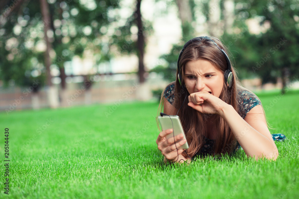 woman in a horror frustration bite his fist looking at phone screen outside