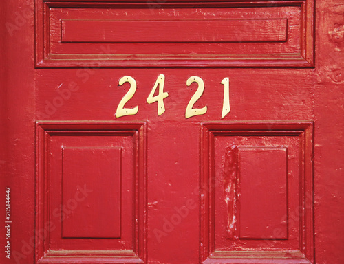 Red wooden door with gold numbers