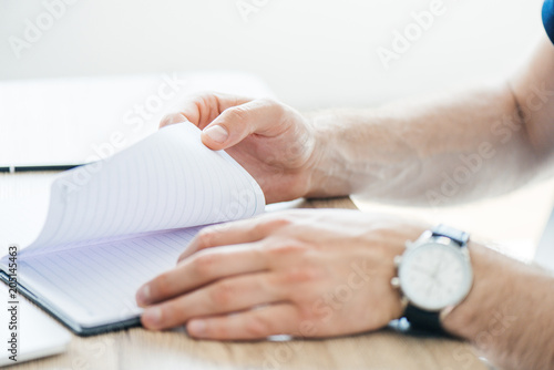 close-up partial view of person holding notepad at workplace