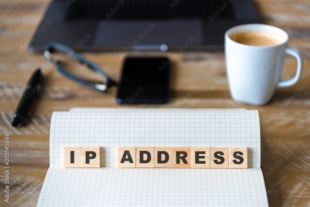 Closeup on notebook over wood table background, focus on wooden blocks with letters making IP ADDRESS words