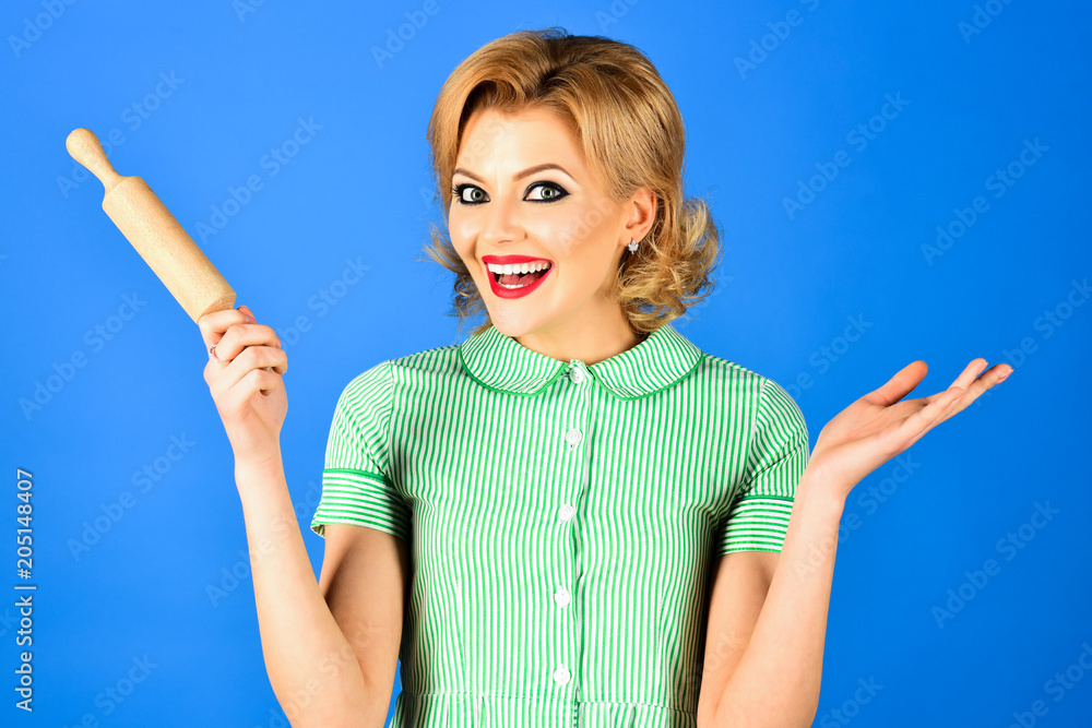 Woman in pin up style holds rolling pin, smiles. Beautiful pinup girl with  perfect makeup with rolling-pin. Blonde woman, gorgeous girl hold rolling  pin. Retro theme. Happy housewife with rolling pin. Stock