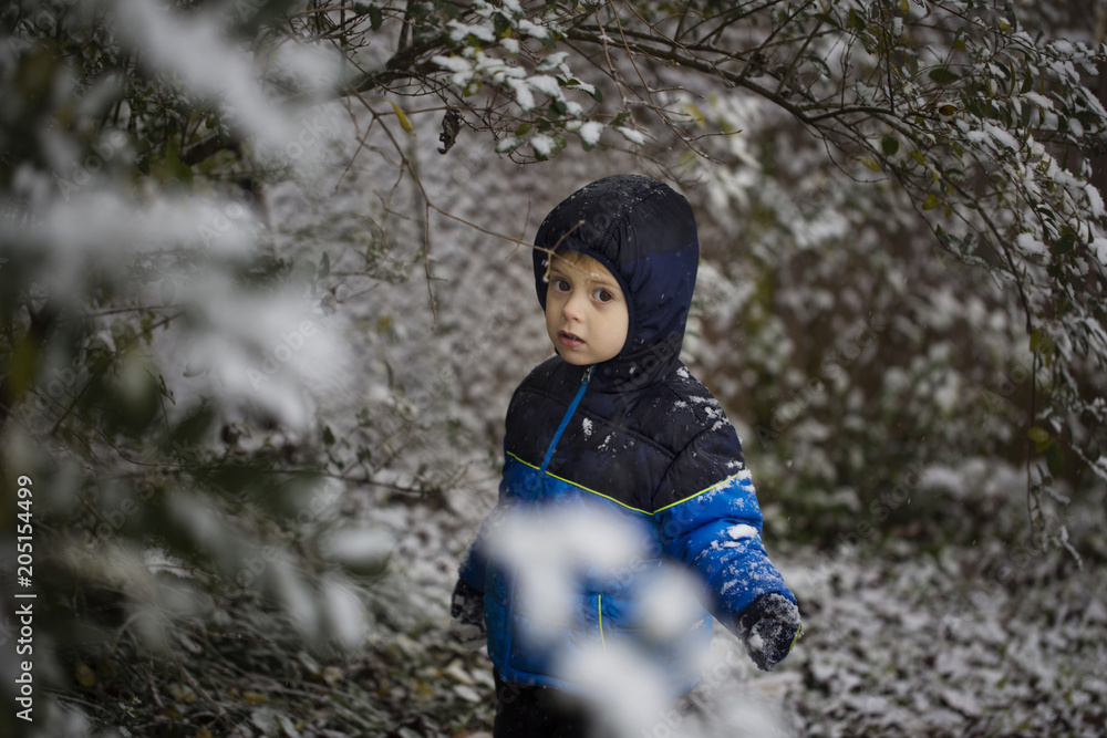 A cute little boy stands in snow in park in the winter, looking at the camera Black & White A cute little boy stands in snow in park in the winter, looking at the camera Black & White