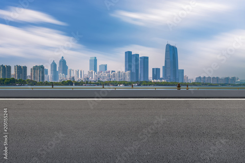 The empty asphalt road is built along modern commercial buildings in China s cities.