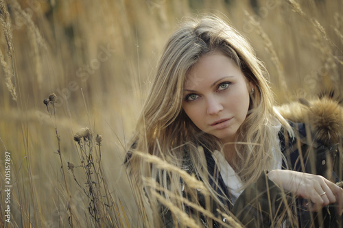 Portrait of beautiful young woman with makeup in high grass looking at the camera