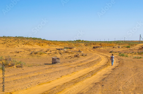 Wells in semi-desert. Girl walking on road in sand place