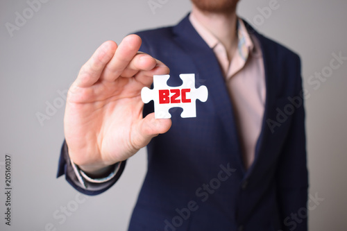 Businessman holding a puzzle with the inscription:B2C © Майя Руднева