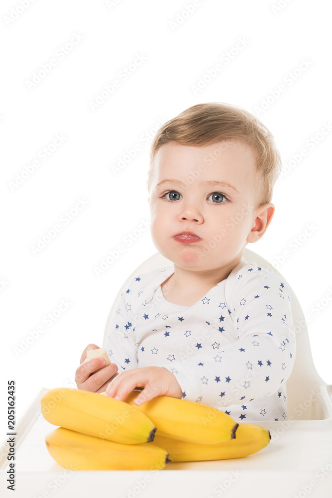 eating baby boy sitting in highchair with bananas isolated on white background eating baby boy sitting in highchair with bananas isolated on white background
