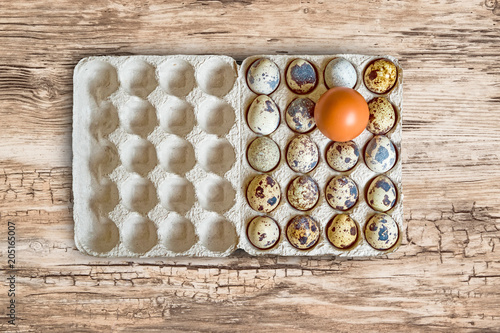 Fresh raw quail eggs in packaging on natural wooden background, close-up flat lay, copy space 