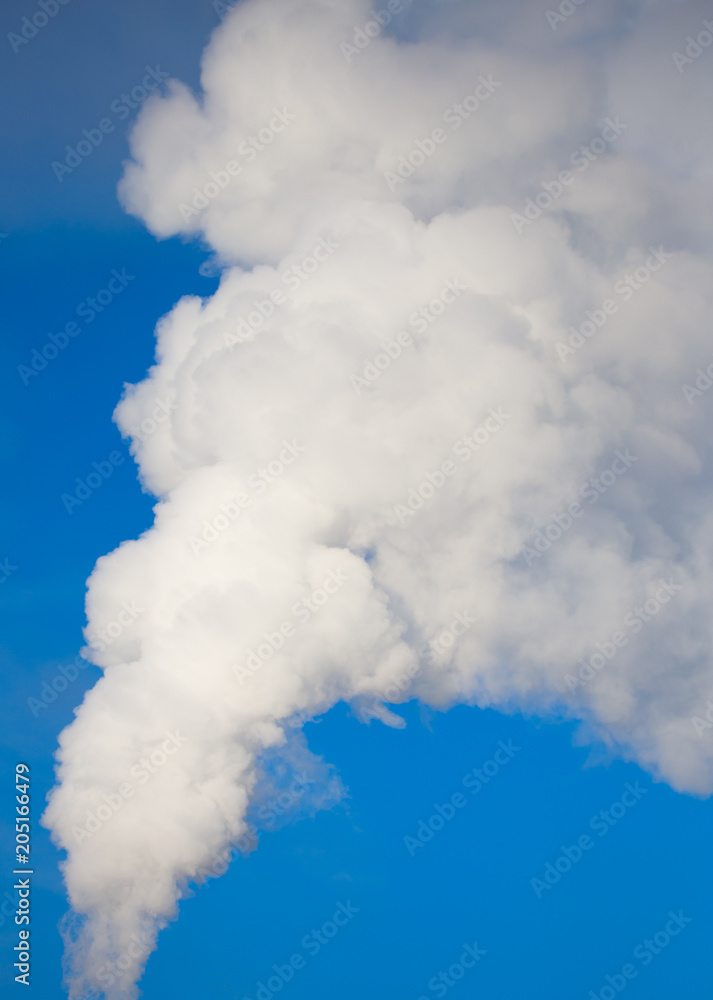 smoke from a pipe in the factory against a blue sky