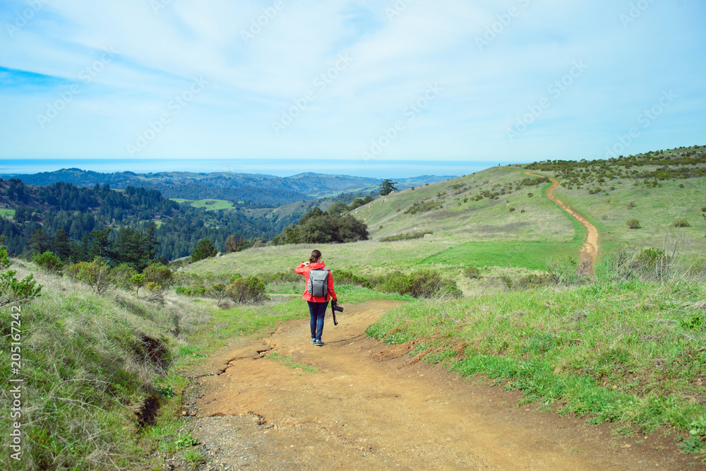 Hiker in red jacket with backpack on trail in beautiful landscape