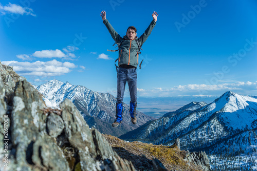 Tourist hikers in the high jump in the background of snowy mountains. Concept of adventure, freedom and active lifestyle