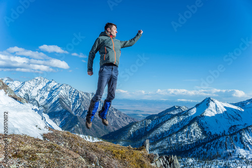 Tourist hikers in the high jump in the background of snowy mountains. Concept of adventure, freedom and active lifestyle