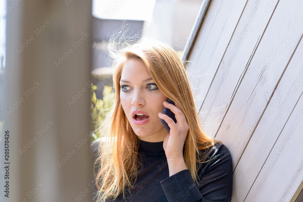 Woman shocked during conversation on mobile phone Woman shocked during conversation on mobile phone