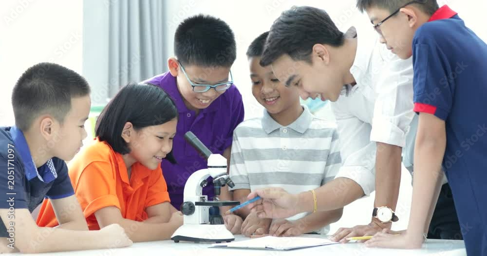 Asian teacher expanding to student in biology class with microscope . Asian teacher expanding to student in biology class with microscope .