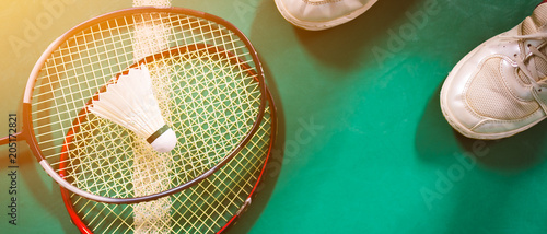 Badminton ball and racket on court floor.