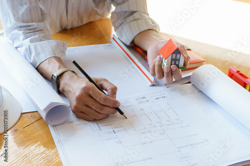 Architect or engineer working on blueprint at workplace on wooden desk. - architectural project, Construction concept.