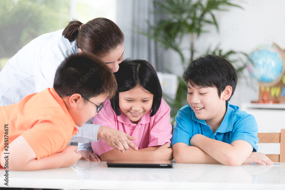 Asian teacher and kids entertaining themselves using digital tablet