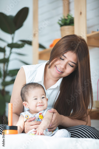 Happy asian family mother with daughter playing on bed with smile face.