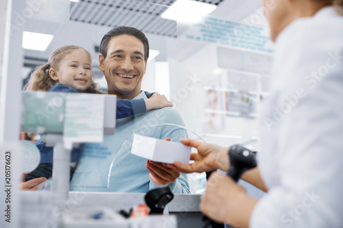 Thank you. Low angle of female pharmacist transmitting medication and jolly man holding girl