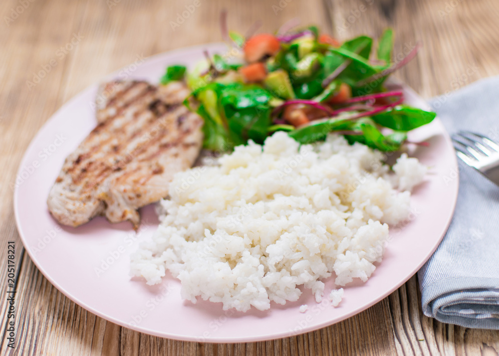 Grilled meat, boiled rice and vegetable salad on a wooden background. Grilled meat, boiled rice and vegetable salad on a wooden background.