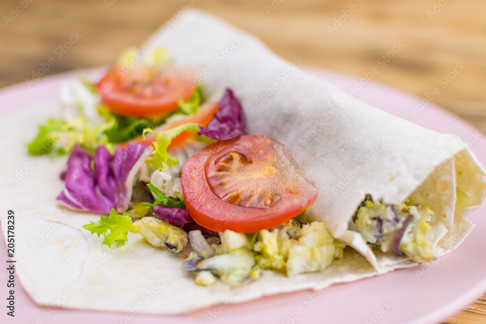 Preparation of a roll of pita bread and fresh vegetables on a wooden background. The concept of healthy eating. Preparation of a roll of pita bread and fresh vegetables on a wooden background. The concept of healthy eating.