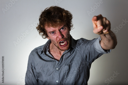 Angry young man shouting and pointing his finger photo