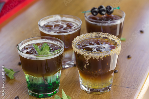 Cold coffees with mint leaves, orange, amarena fruits and ice cubes