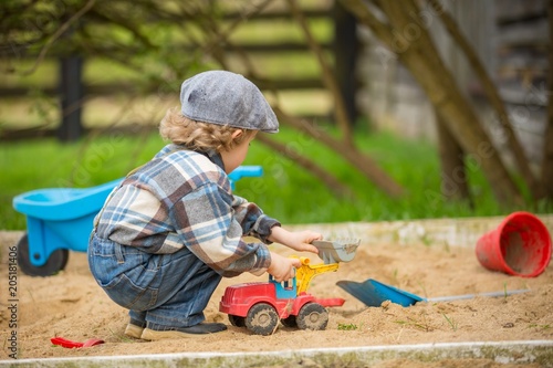 Fotografie Small caucasian boy playing in sandpit