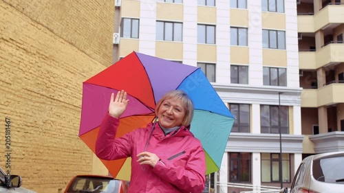 Senior woman with colorful umbrells meet someone at the street photo