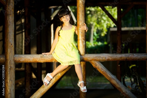 Baby girl in bright yellow dress sits on a log