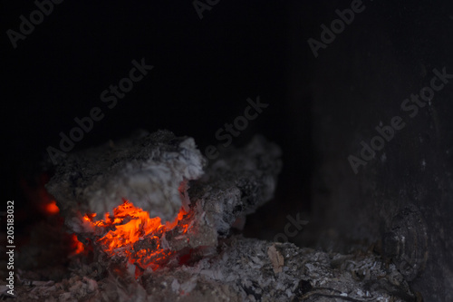 Burning coals and ashes in an iron stove, close-up