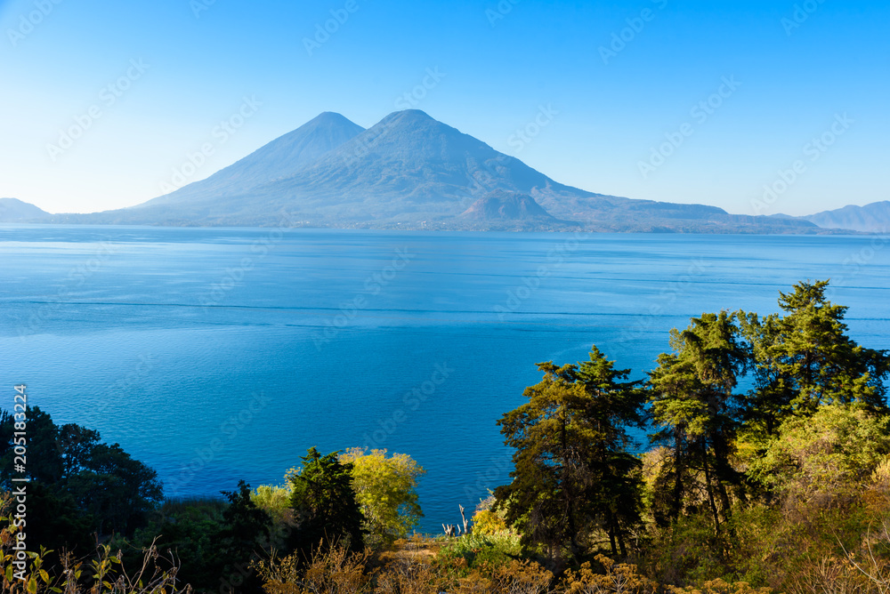 View from Lake Atitlan in the early morning, blue skys and clear water, beautiful magic lake with volcanos and indigenous people in the highland of Guatemala 