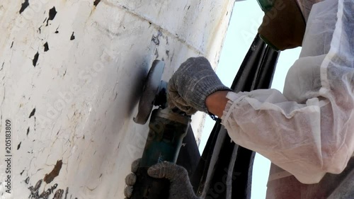 Workers tear off paint on metal in repairs process at shipyard. Working people in overalls reconstruct at ship repair yard outdoors in port.