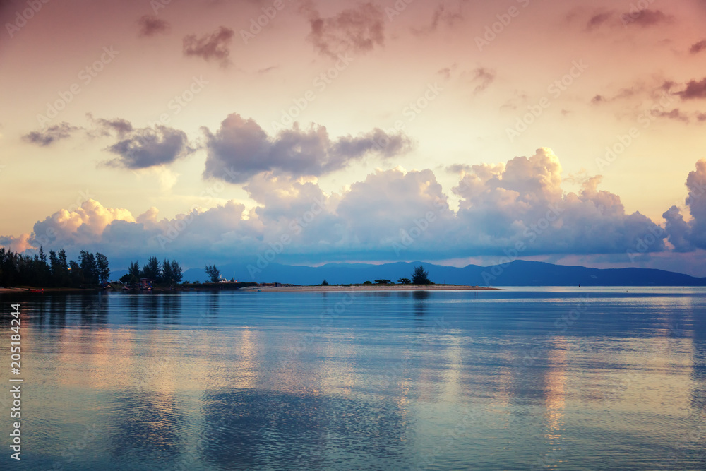 Bright colorful stunning sunset on a tropical beach on the island paradise, reflection of clouds in the surface of the water