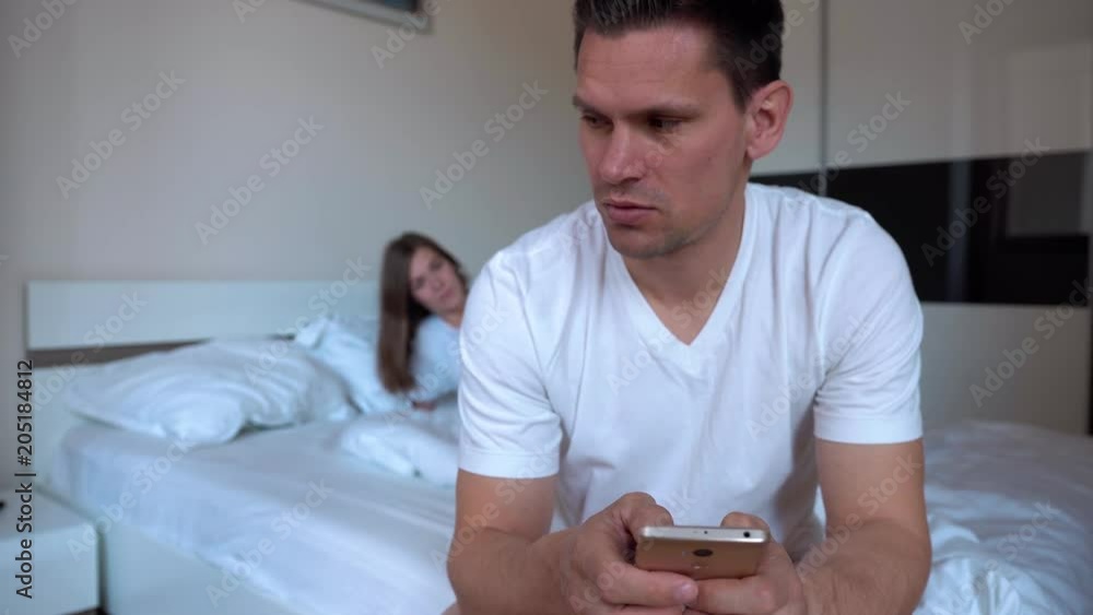 Blurred Wife Woke Up From The Noise Of The Smartphone On Which Her Husband Plays In The Middle Of The Night, Asks Him To Go To Bed But He Continues To Play Blurred Wife Woke Up From The Noise Of The Smartphone On Which Her Husband Plays In The Middle Of The Night, Asks Him To Go To Bed But He Continues To Play