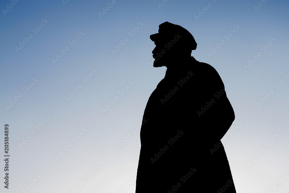 Black silhouette of a monument to Vladimir Ilyich Lenin against the blue sky