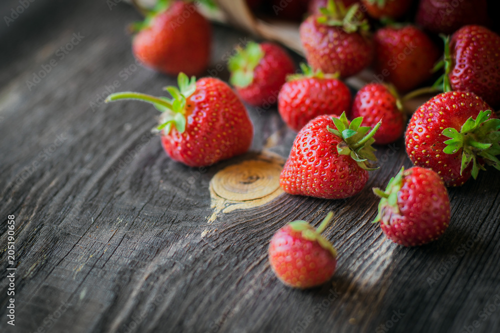 strawberry is scattered from a basket on wooden background