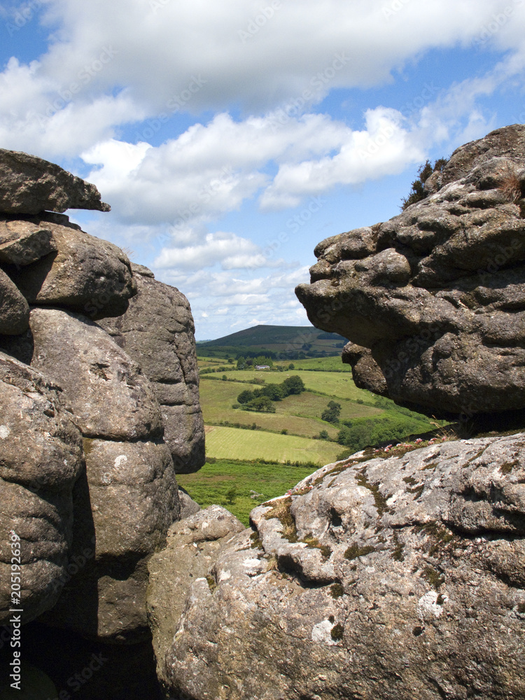 Dartmoor countryside glimpsed through a gap in the rock formations of  Hound Tor, Devon, UK