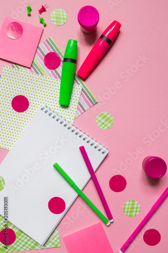 Pink and green markers and notepad for writing on a pink background flat top view with copy space, pattern from stationery accessories for school