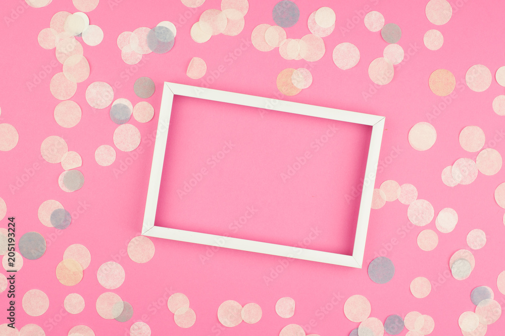 White picture frame and confetti on blue background. Top view, flat lay. Mockup for party or birthday invitation. White picture frame and confetti on blue background. Top view, flat lay. Mockup for party or birthday invitation.