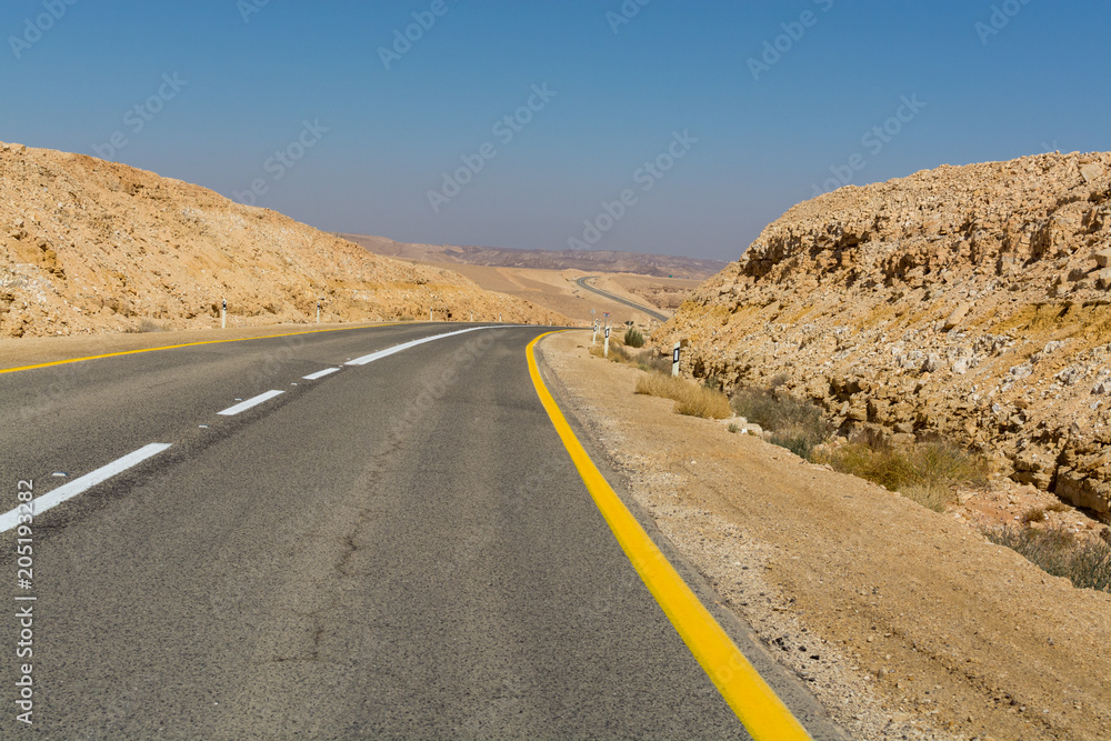 Asphalt road in desert Negev, Israel, road 40, transport infrastructure in desert, scenic mountains route from Eilat to north of Israel Asphalt road in desert Negev, Israel, road 40, transport infrastructure in desert, scenic mountains route from Eilat to north of Israel