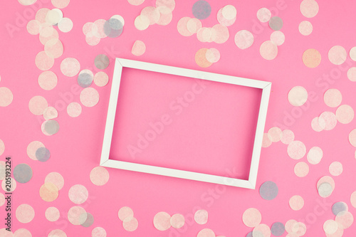 White picture frame and confetti on blue background. Top view, flat lay. Mockup for party or birthday invitation. © katjabakurova