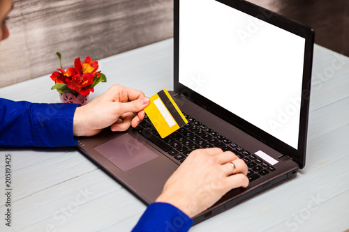 Man hold credit card  in hand and entering security code using laptop keyboard at home. Technology, banking, home, lifestyle and online shopping conceptconcept photo