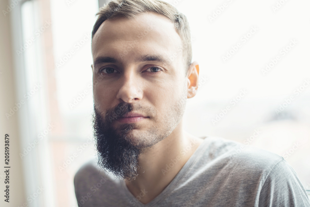 Handsome man half beard standing in front of white background with half of  his face with scruffy beard, the other half has a beautiful trimmed beards  and smart look hair style Stock