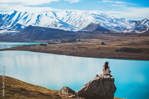 A girl with long hair sit on a rock in Mt. John looking at Lake Tekapo photo