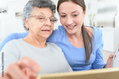 фотографія granddaughter showing old lady how to use tablet