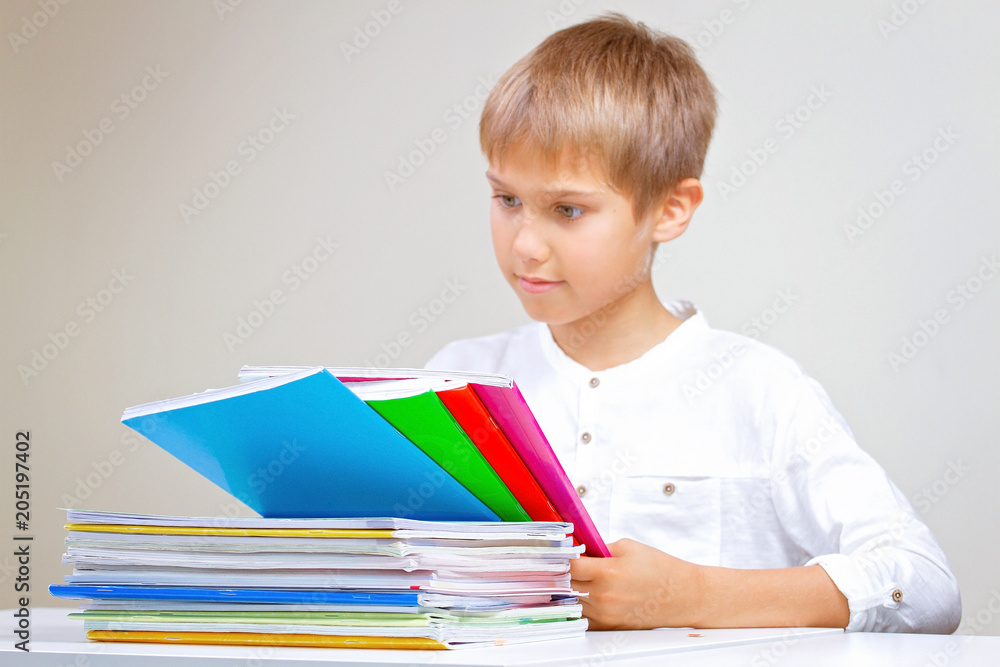 Child doing his homework at home. The boy sitting and looking in to books, notebooks and textbooks