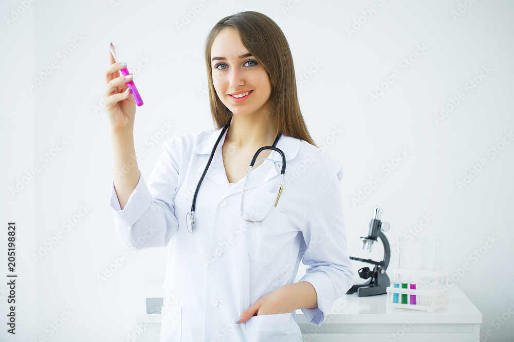 Female medical or research scientist or doctor using looking at a test tube of clear solution in a lab or laboratory.