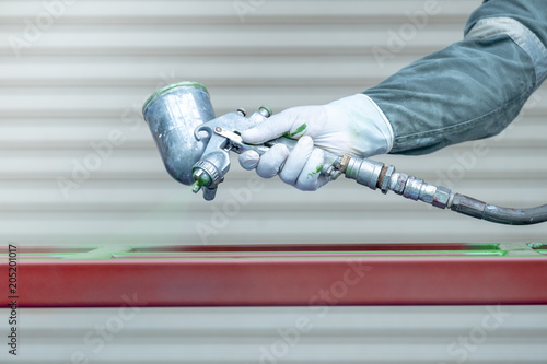 Workers spraying paint on metal work.
