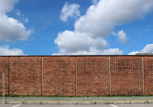 Photography Brick wall and a green sidewalk under a blue sky with big clouds